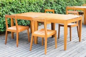 Solid wood outdoor dining table and chairs on a backyard deck.